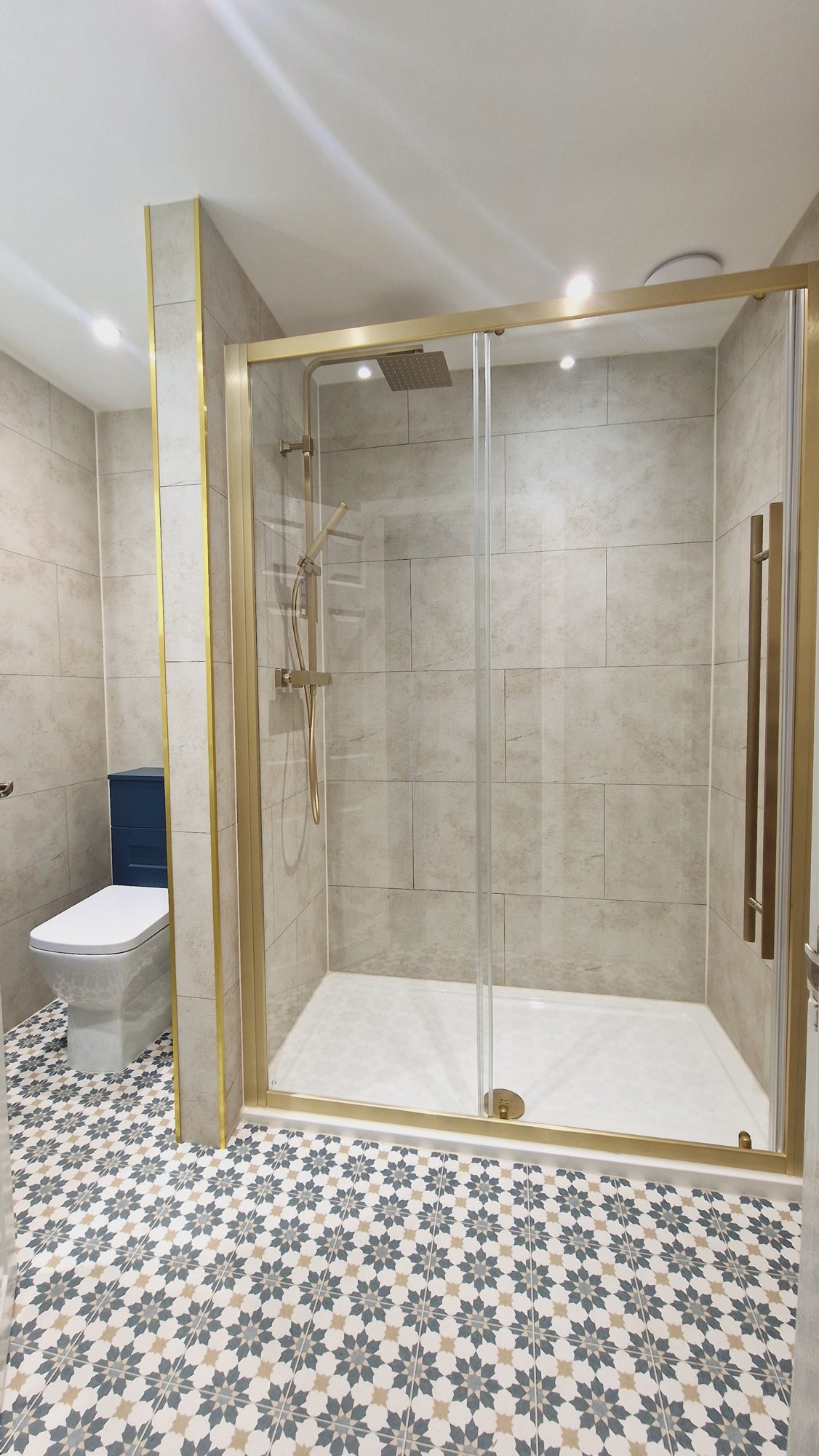 A walk-in shower with brass-framed glass doors above a star-pattern tiled floor