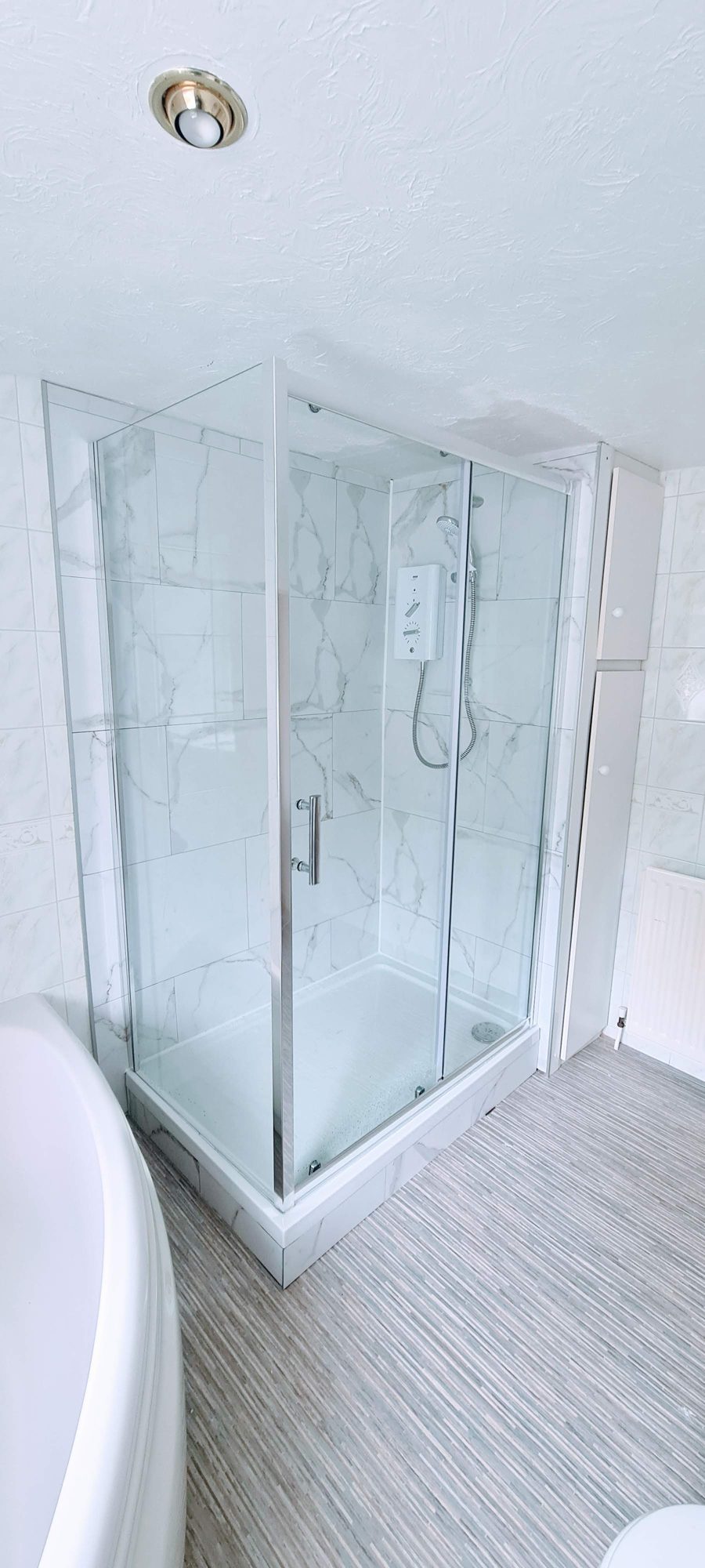 A glass corner shower enclosure with marble-look walls